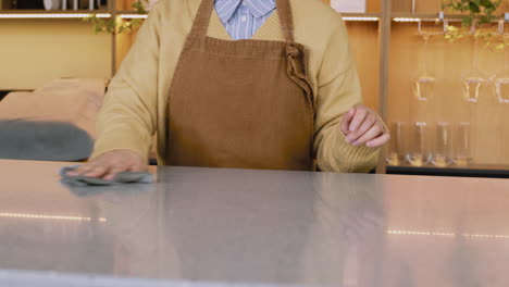 Unrecognizable-Waitress-Cleaning-Bar-Counter-With-Rag-While-Working-In-Coffee-Shop