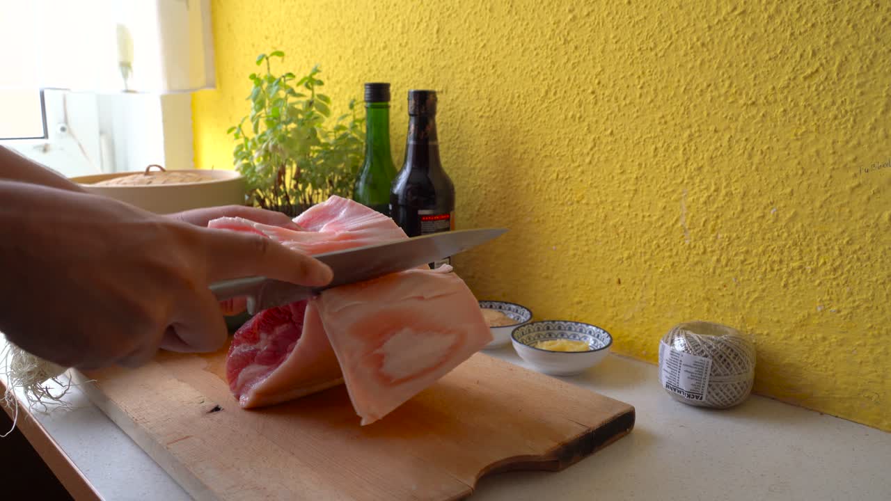 mandlige hænder skærer hud og fedt af svinekød i køkkenet