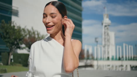 attractive woman putting earbuds in ears starting phone call at street close up