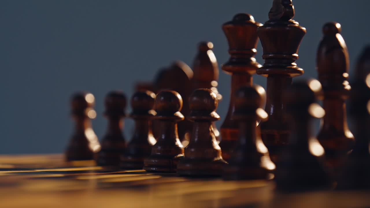 Black wooden chess pieces aligned across classic grid closeup. Strong sunlight