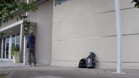 Adventorous-man-tying-up-a-hammock-on-the-side-of-building-and-laying-down-to-relax-in-it