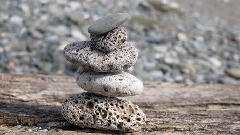 small textured beach rocks balanced zen like on wooden beach sleeper closeup left dolly