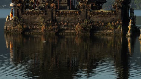 ascending slow motion shot of beautiful water temple on bali panoramic shot of pura segara ulun danu batur temple on volcanic lake batur on bali in indonesia