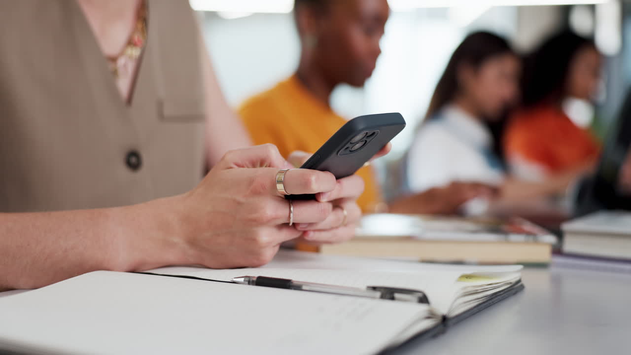 Gros plan sur des mains écrivant un message sur un téléphone portable dans un bureau
