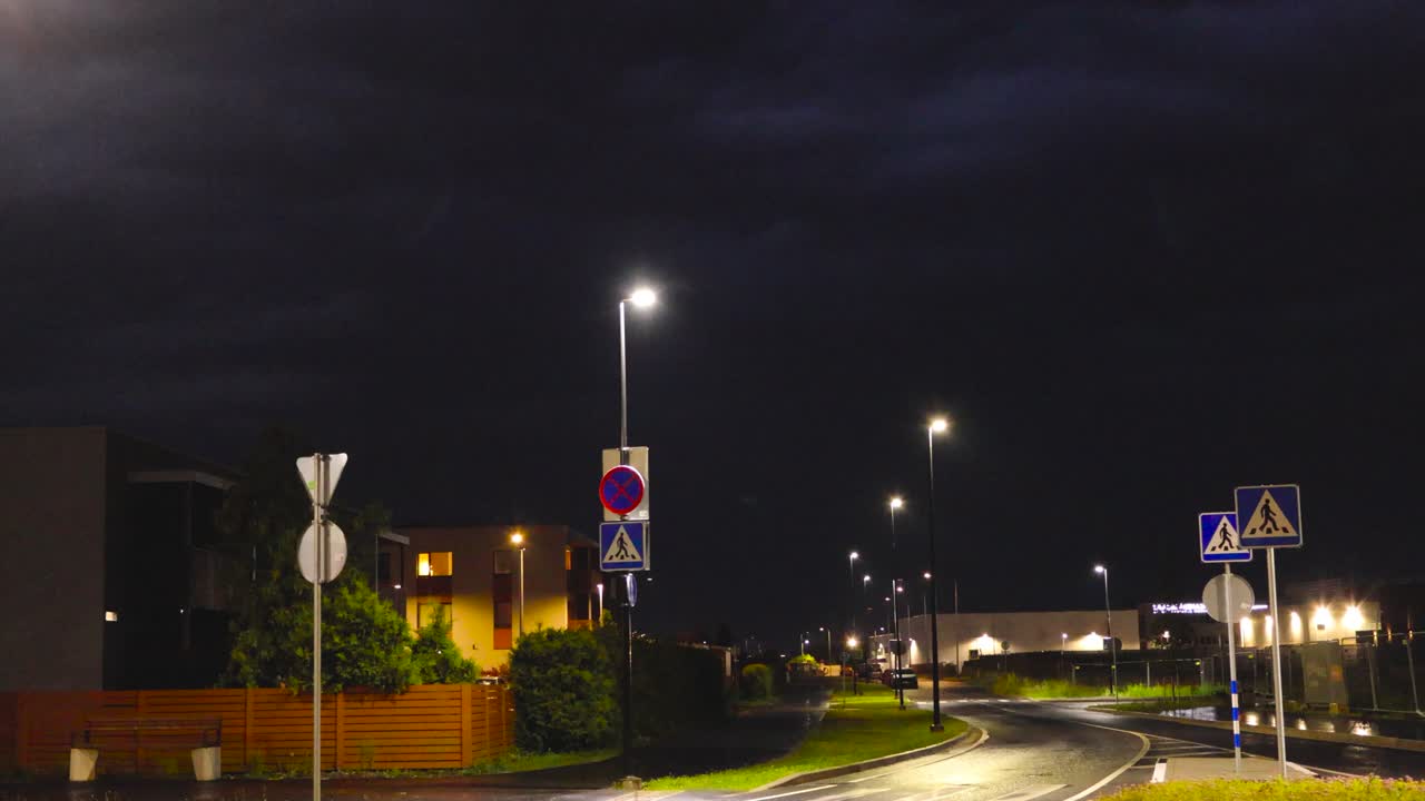 Dark dramatically colored blue and black storm hurrican sky during a thunderstorm when lightning occasionally strikes in the back of a residential housing area with apartments during a summer night