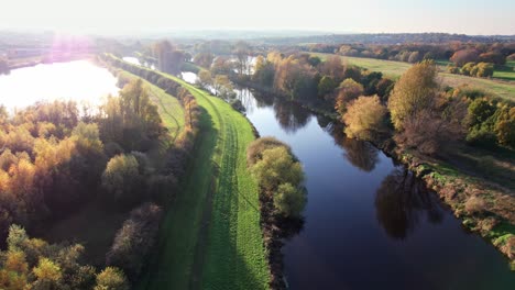 imágenes aéreas de un río que aún fluye con un espejo como reflejo del cielo, con camino de hierba, pasarela y árboles