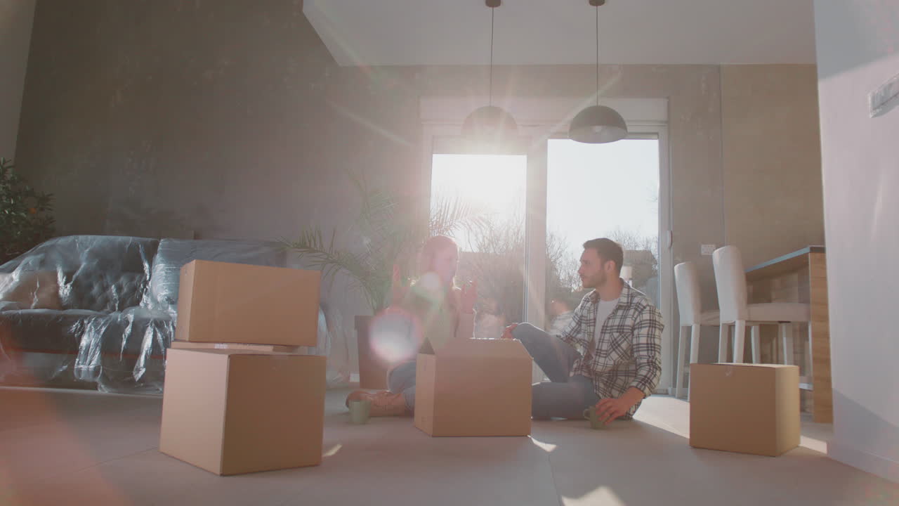 una pareja joven desempaquetando una nueva caja de cartón.