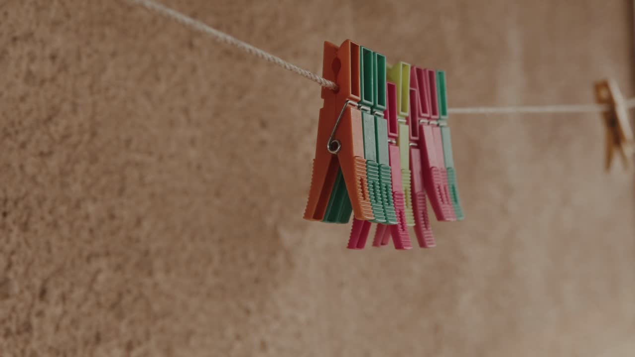 Plastic clothespins clipped on rope clothesline in simple domestic scene