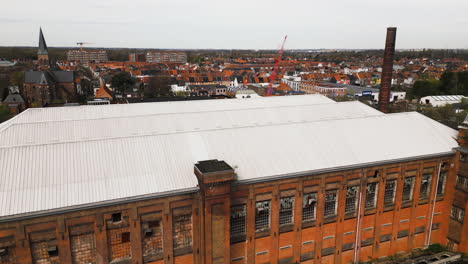 Ghent-cityscape-and-old-abandoned-building-bellow,-aerial-descend-view