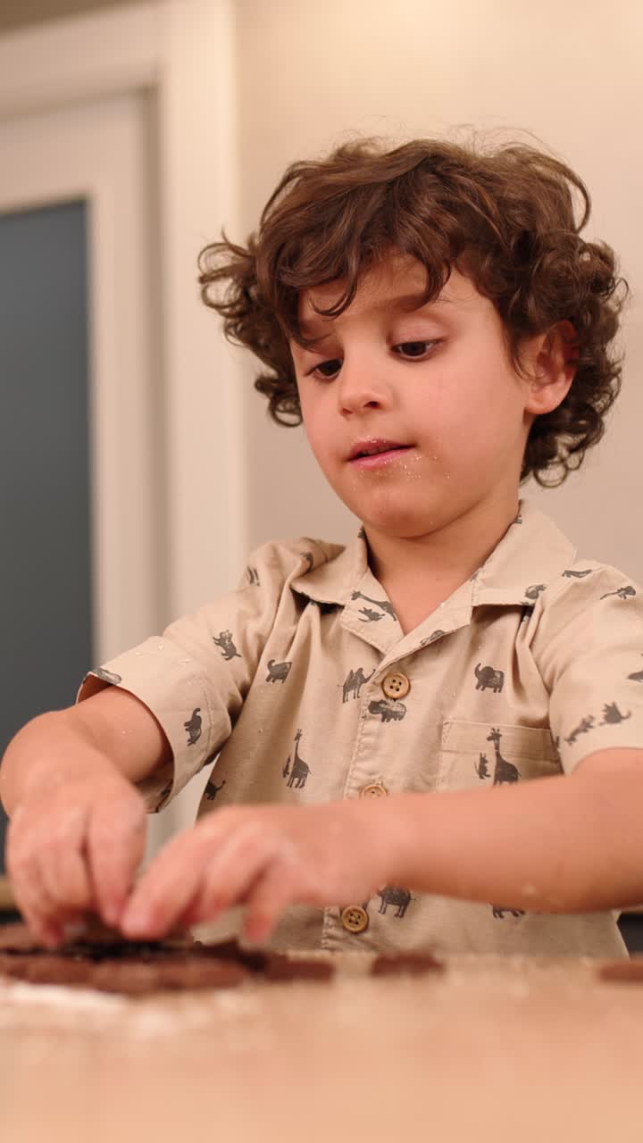 Child kneading chocolate dough on kitchen table