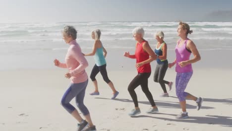 Animation-of-text-vibes,-in-white-and-black,-over-women-running-on-beach