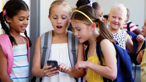 Niños-De-Escuela-Usando-Teléfono-Móvil-En-El-Pasillo