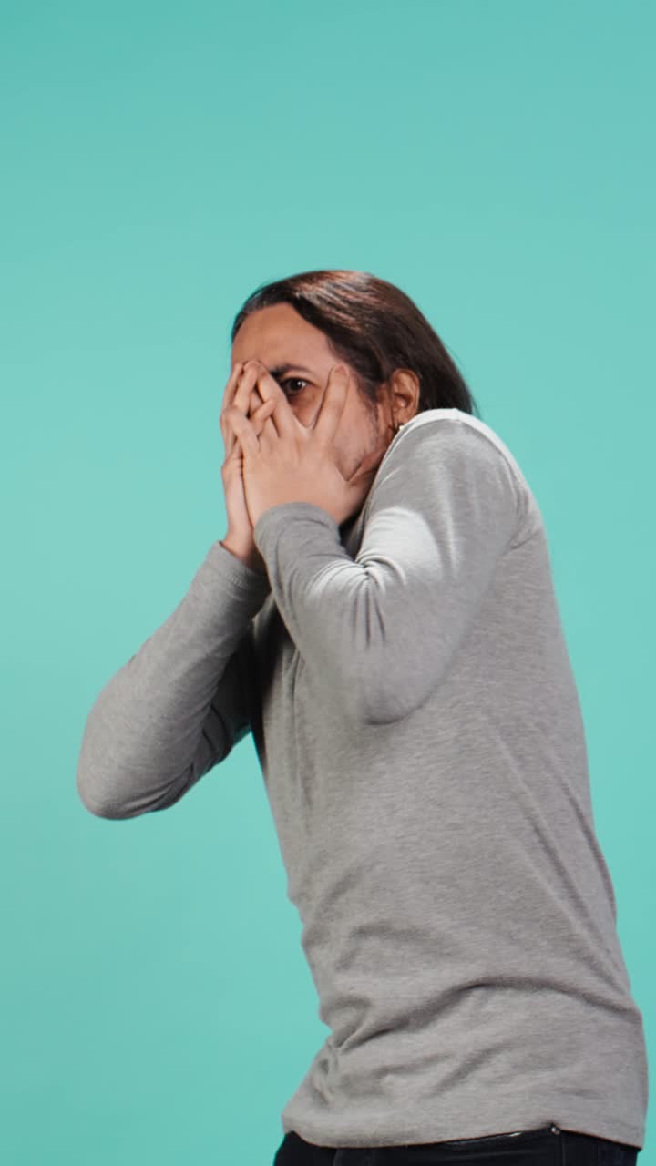 Vertical video Portrait of frightened man covering his face with hands, feeling distraught