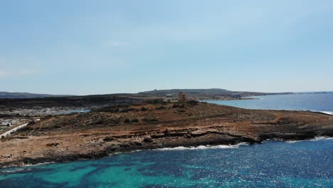 vista aérea de la playa de coral hacia la torre blanca en mellieha armier bay, malta