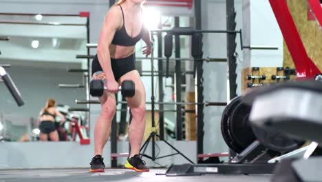 fitness a muscular female athlete trains in the gym with heavy dumbbells. crossfit. slow motion 200 fps