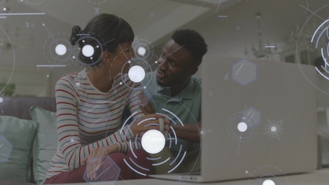 Leaning couple meeting eyes after laptop prompt on sofa, man gesturing, woman holding mug, HUD