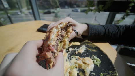 un tipo comiendo una hamburguesa en un restaurante.