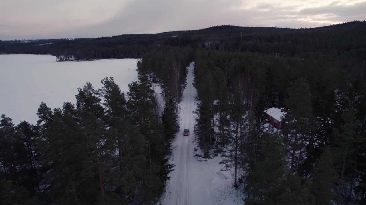Vinterväg vid en frusen sjö med en blå bil som kör förbi.