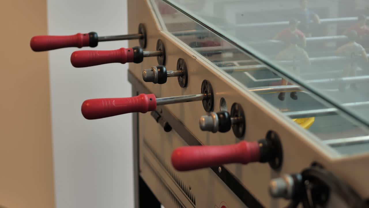 Close-up view of old vintage foosball handles moving slowly along the table - 4K