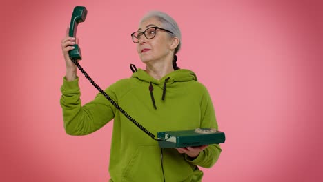 Crazy-elderly-granny-old-woman-talking-on-wired-vintage-telephone-of-80s,-fooling-making-silly-faces