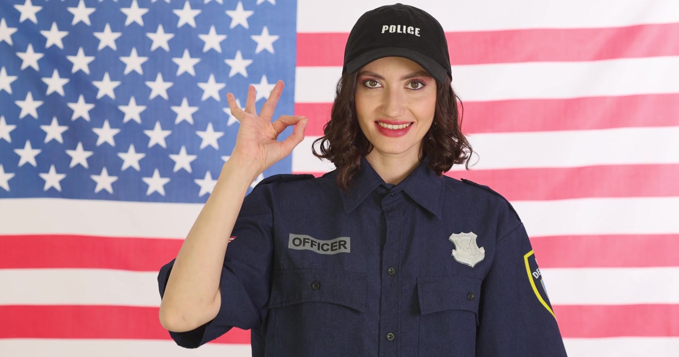 Poliziotta fa un occhiolino giocoso sullo sfondo della bandiera americana.