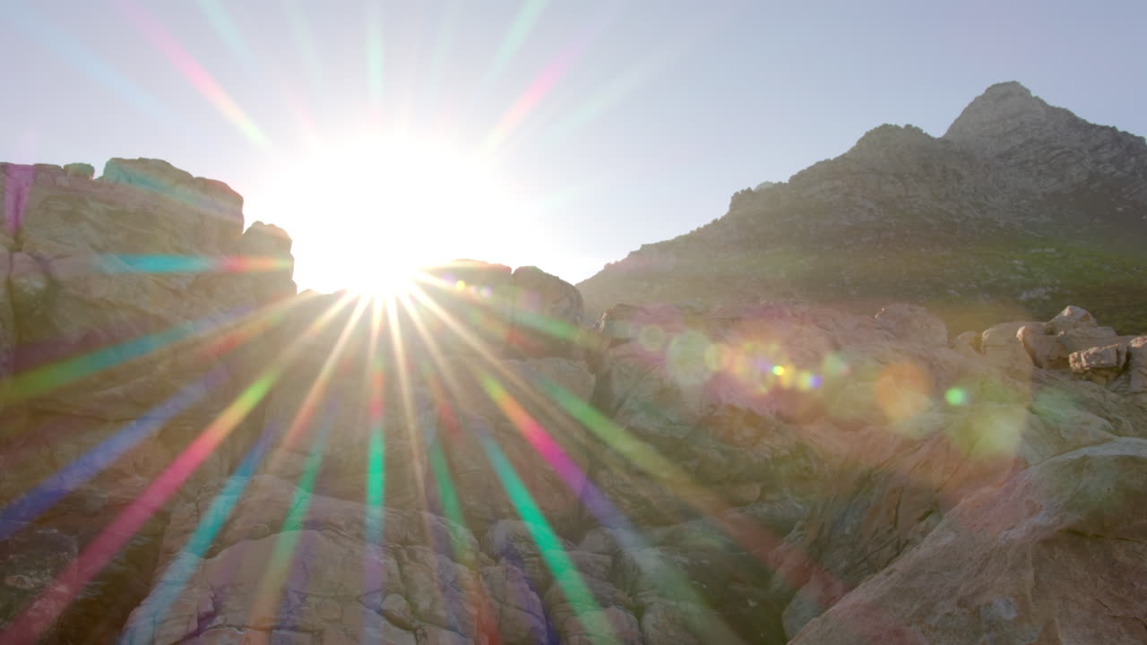 Sunrise over rocky mountain peaks, creating vibrant lens flare effect, copy space
