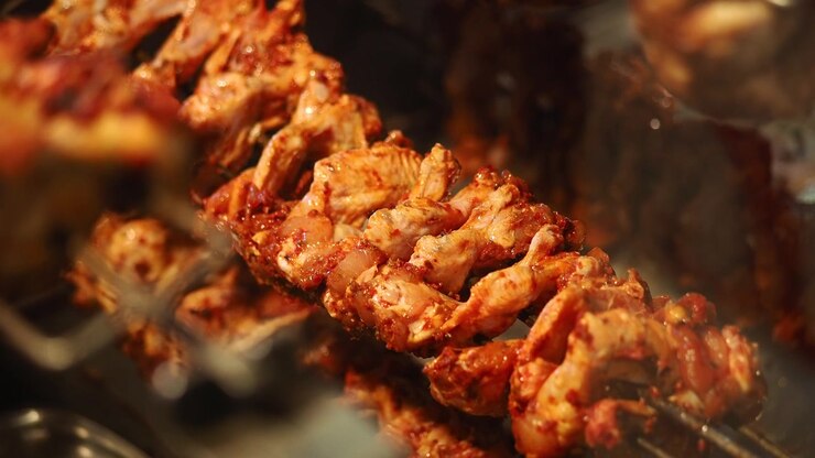 Pollo allo spiedo in cottura su uno spiedo rotante
