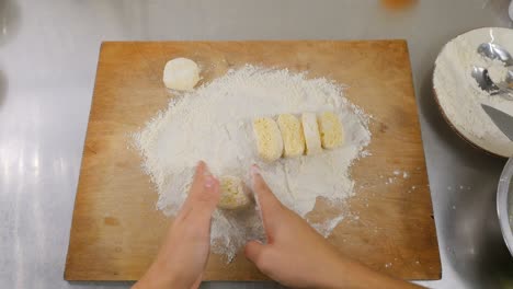 primer plano - el cocinero esculpe panqueques redondos de queso en una tabla de madera