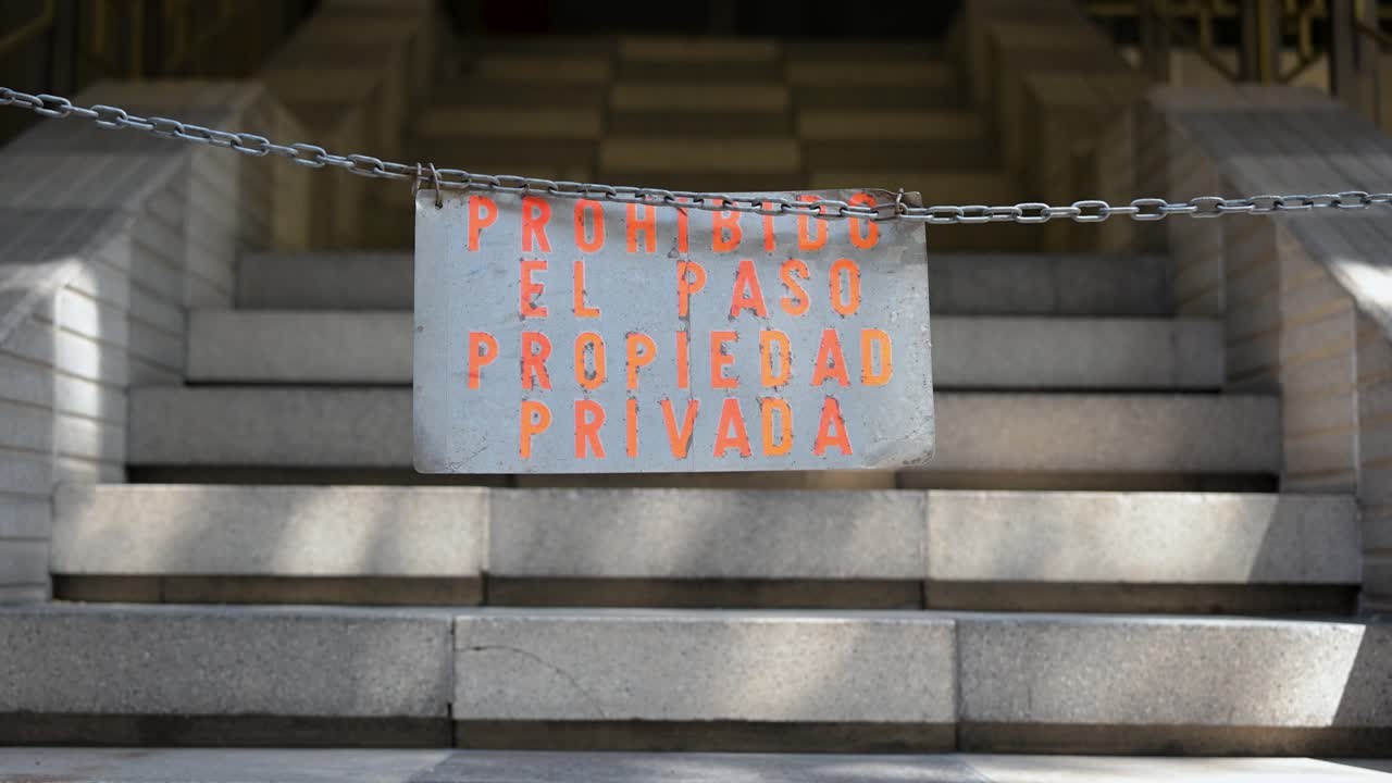 A metal chain is stretched across stone steps, reinforcing a sign that reads "Propiedad Privada" (Private Property). A physical barrier to prevent unauthorized entry