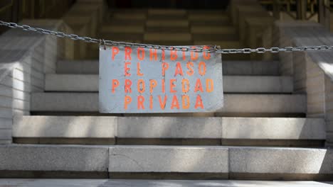 a metal chain is stretched across stone steps, reinforcing a sign that reads "propiedad privada" (private property). a physical barrier to prevent unauthorized entry