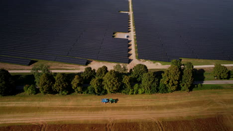 aerial view of large scale solar panel farm with tractor driving past