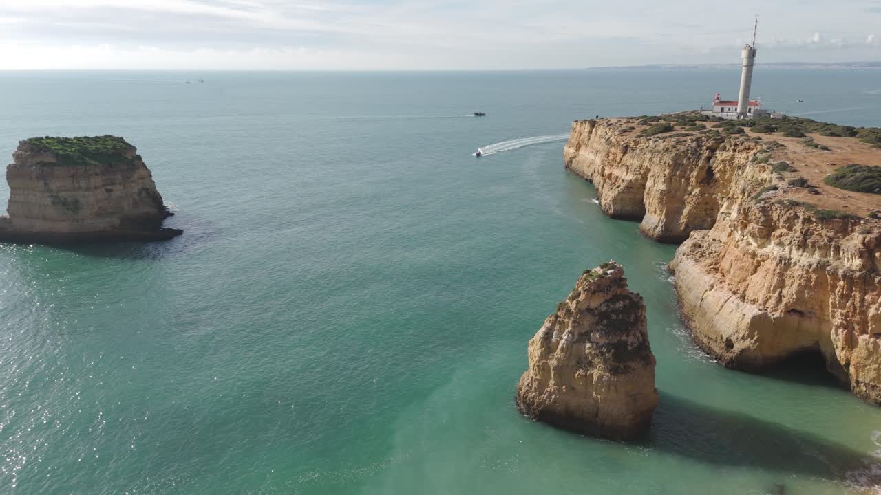 Dron aéreo capturando los escarpados acantilados de Ferragudo con un faro costero con vistas al océano Atlántico a lo largo de la costa del Algarve
