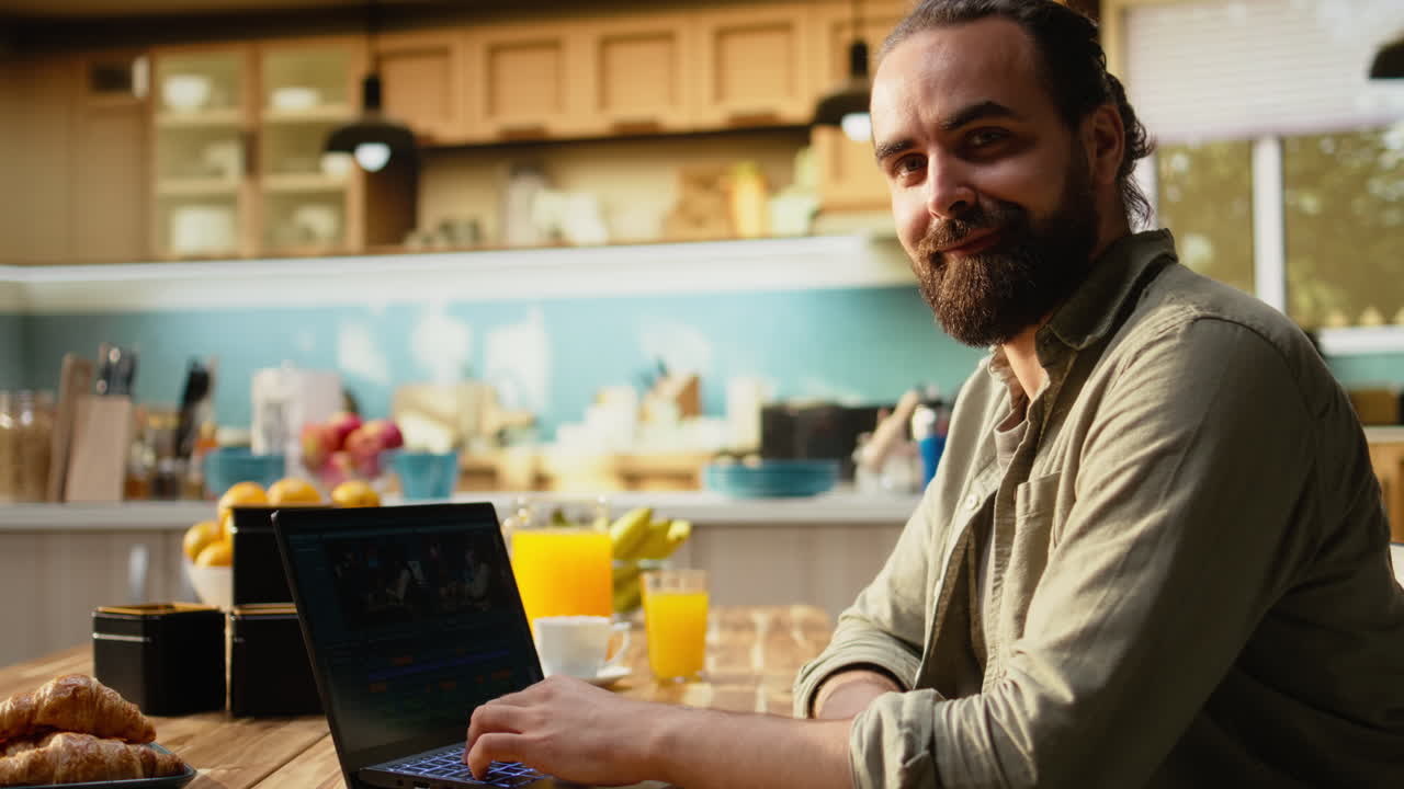 Ritratto di un creatore di contenuti che modifica video sul laptop al tavolo della cucina