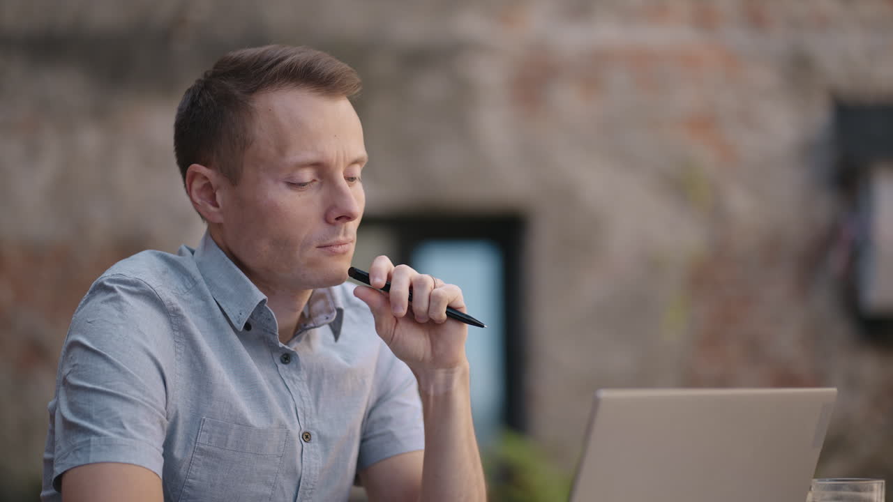 Thoughtful 30s man thinking of problem solution working on laptop. Serious doubtful male professional looking away at laptop considering market risks making difficult decision sitting at desk