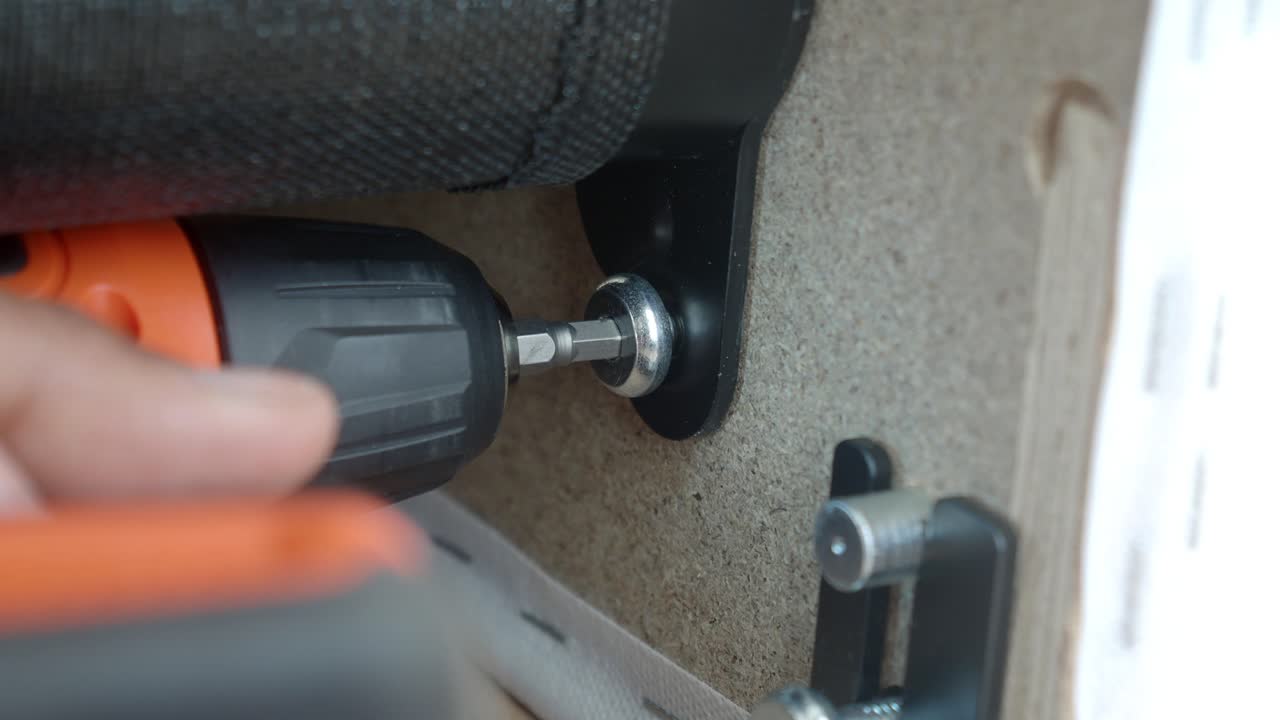 Close-up of a person using a power drill to assemble or repair an item