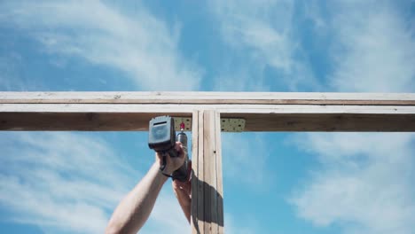 man screwing steel corner mounting plate for joining wooden structures