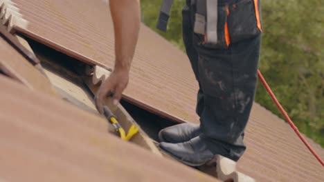 closeup of worker using crowbar to remove roof tiles for solar panel, day