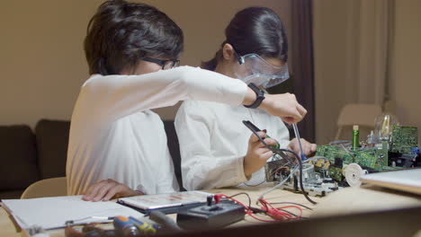 Two-geek-children-sitting-at-desk-and-doing-project-work