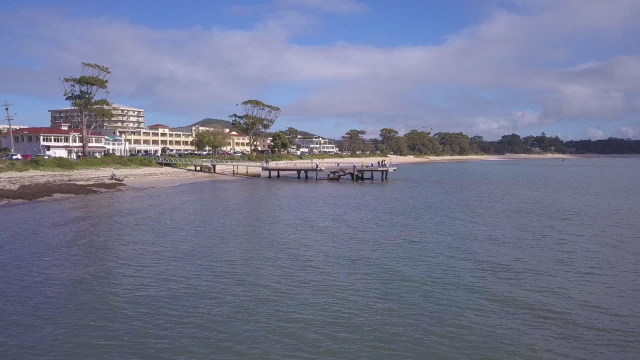 Aerial drone flying low toward a pier at the beachfront houses or property