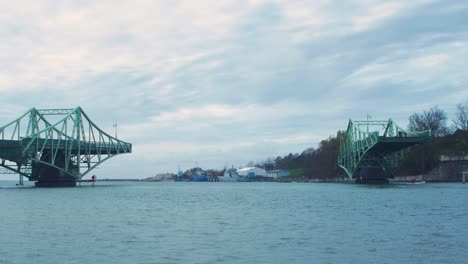 Oskara-Kalpaka-swing-bridge-closing-in-Liepaja-in-cloudy-autumn-day,-wide-shot