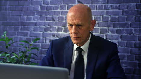 a mature business man working on a laptop computer at night on a dark office