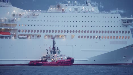 tugboat next to cruise ship in norway. wide