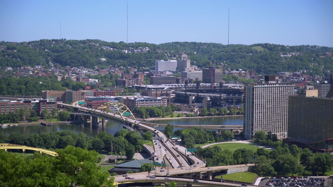 Pittsburgh, Pensilvanya'ya doğru uzanan otoyol üst geçit kavşağını, yeşil tepeleri ve nehri tepeden gören yüksek havadan drone görünümü.