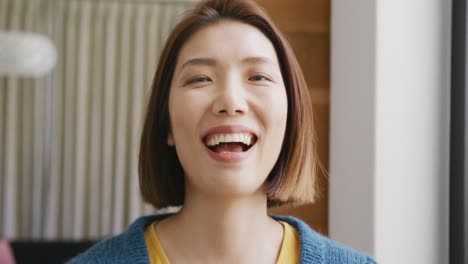 video portrait of happy asian woman smiling and laughing to camera at home