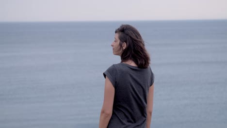 chica de pie sobre un acantilado y mirando al mar, cámara lenta