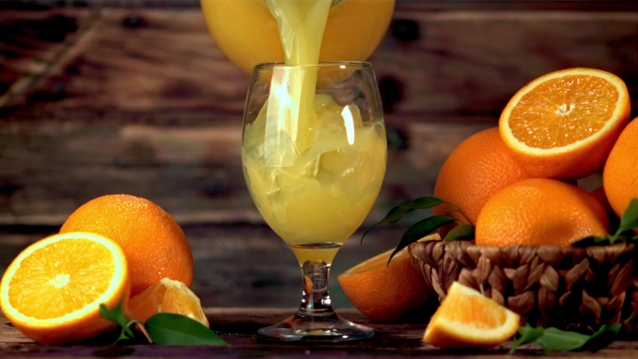 Fresh Orange Juice Poured into a Glass on a Wooden Table