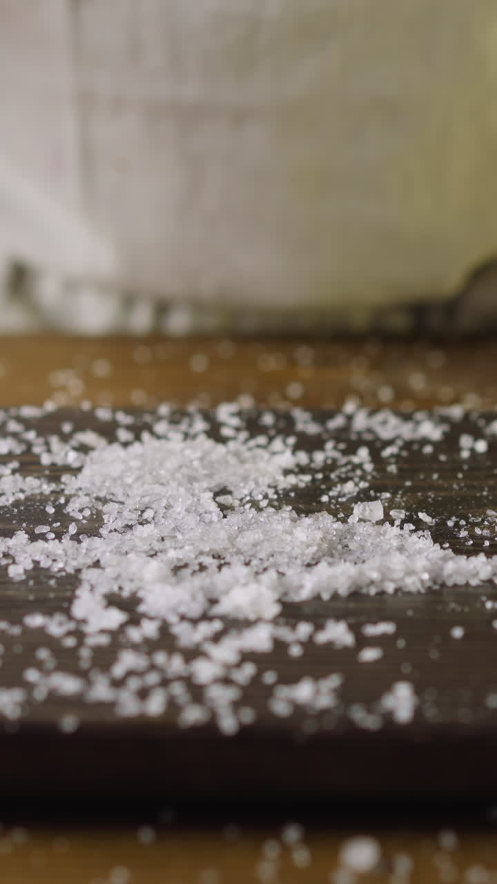 Chef throws fat pickled herring into salt pile on wooden cutting board in kitchen close view. Healthy nutrition of seafood products