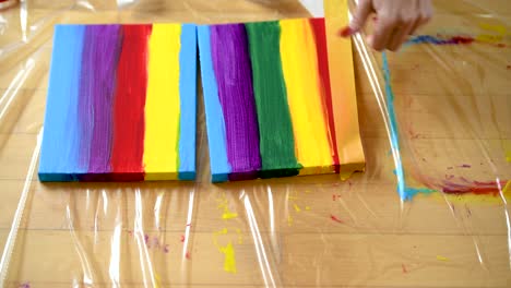 A-woman-using-painters-tape-to-finish-her-colorful-stripes-on-a-canvas