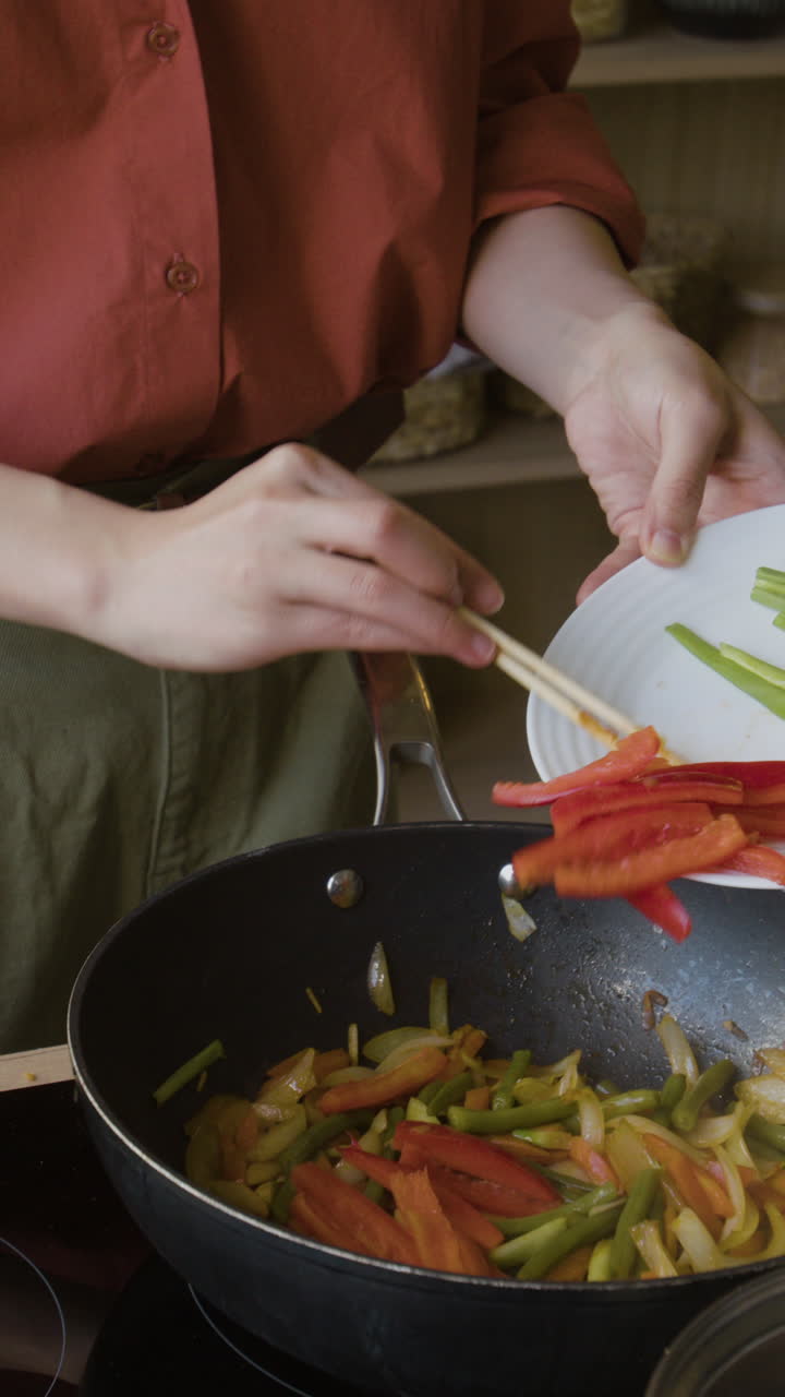 Person stir-frying vegetables in a wok with chopsticks