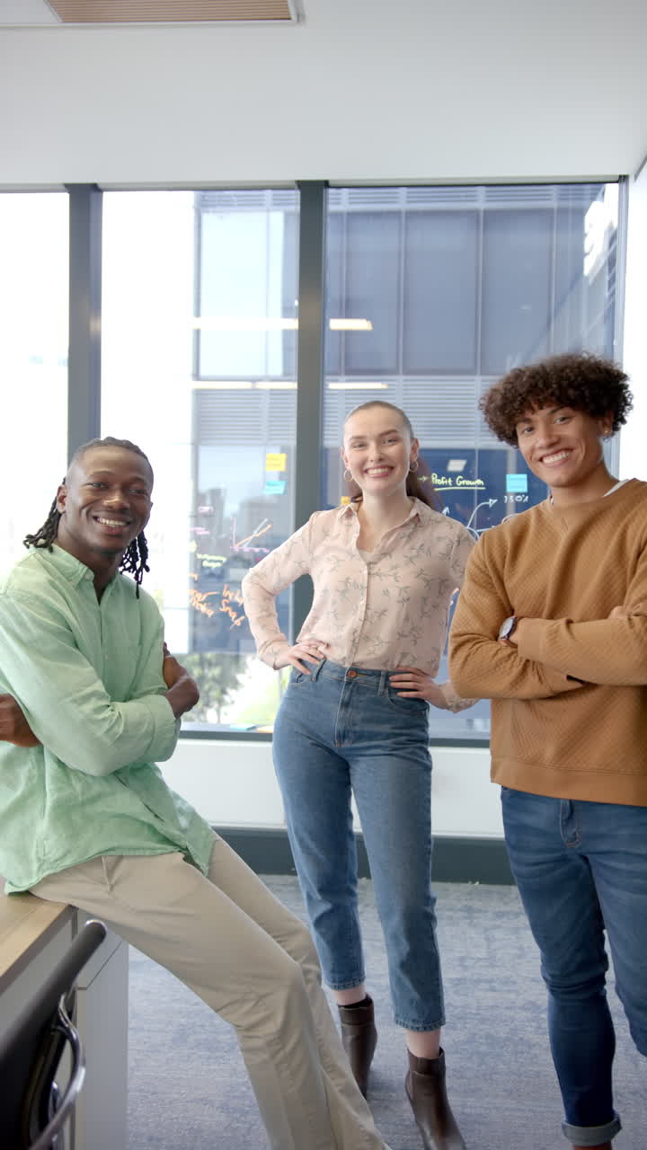 Vertical video: Standing together in modern office, smiling colleagues posing confidently